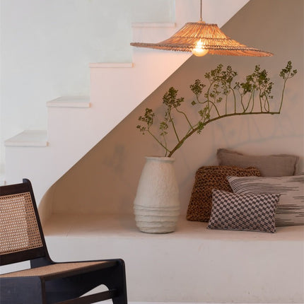 Suspension Cancun en rotin naturel allumée dans une niche sous escalier avec coussins et vase
