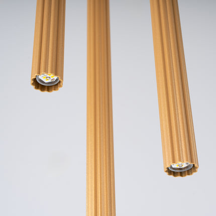Détail de la finition dorée striée des tubes de la suspension cannelée 3 lumières.