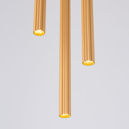 Détail texturé des stries des tubes cannelés dorés, sous un éclairage naturel.