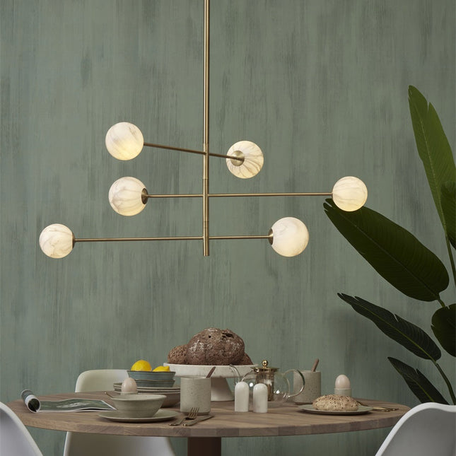 Suspension Carrara 6 globes en verre effet marbre blanc et structure dorée au-dessus d'une table