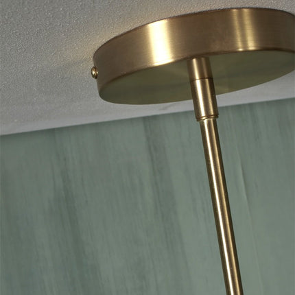 Détail d'un bras doré et de son globe en verre effet marbre sur la suspension Carrara