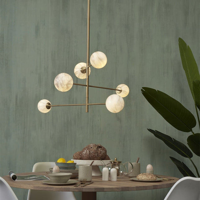 Gros plan de deux globes en verre effet marbre de la suspension Carrara et de la structure dorée