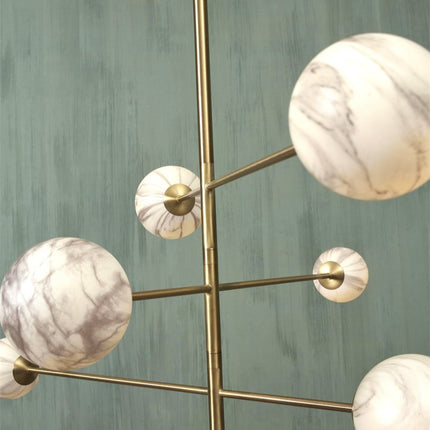Suspension Carrara 6 globes marbre et or suspendue au-dessus d'une table de salle à manger