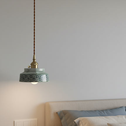 Suspension en céramique peinte motif bleu allumée près d'une tête de lit beige dans une chambre