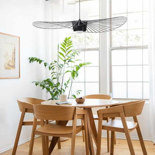 Suspension chapeau filaire noire suspendue au-dessus d'une table à manger en bois