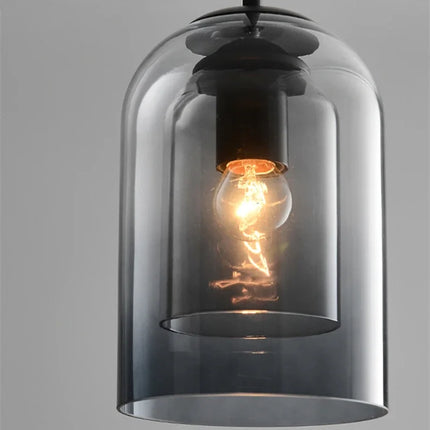 Gros plan sur la double paroi de verre gris fumé et l'ampoule filament de la suspension