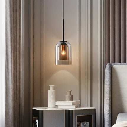 Suspension cloche en double verre marron au-dessus d'une table de chevet dans une chambre