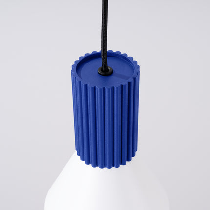 suspension cône blanc à fût cannelé bleu outremer, vue sur fond coloré