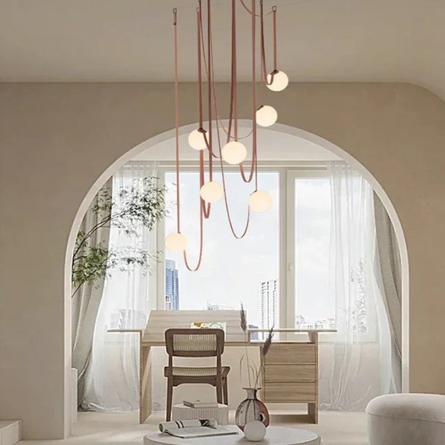 Suspension en cuir cognac et globes en verre opalin installée au-dessus d'une chambre contemporaine.