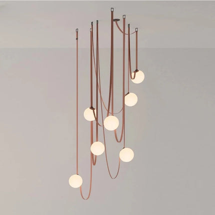 Suspension en cuir cognac à sept globes en verre opalin, composition suspendue au-dessus d'un salon élégant.