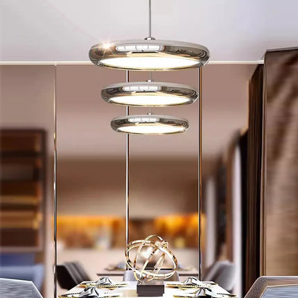 Trois suspensions galet chromées étagées en cascade au dessus d'une table dressée, ambiance chaleureuse