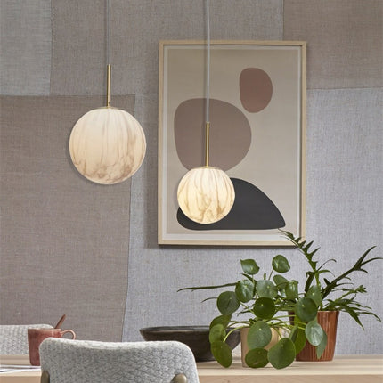 Suspension Carrara en verre effet marbre et métal doré allumée sur fond blanc