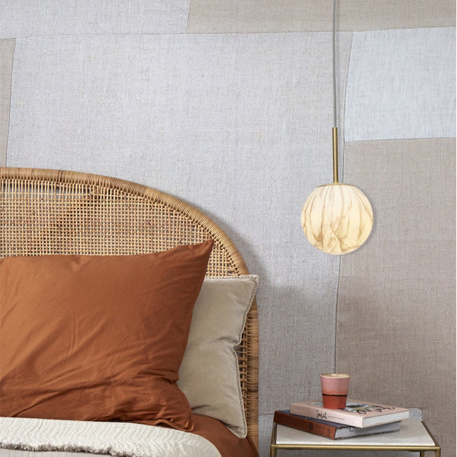 Suspension Carrara en verre effet marbre au-dessus d'une table de chevet dans une chambre au style naturel