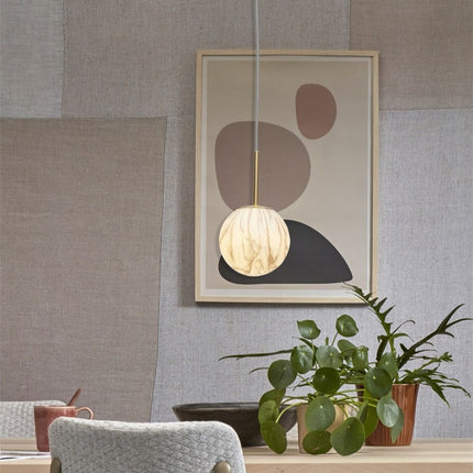 Suspension globe effet marbre allumée devant un tableau abstrait dans une salle à manger