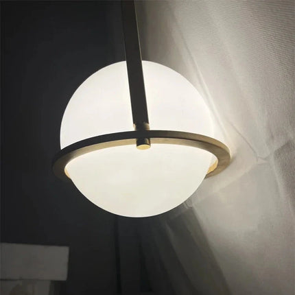Nordische Globus-Pendelleuchte in Weiß und Gold in einem gemütlichen Schlafzimmer