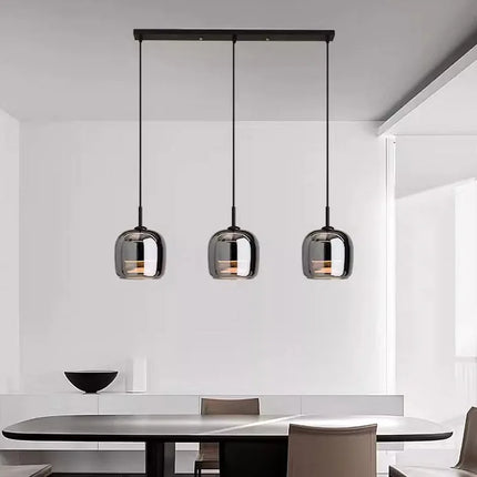 Trois suspensions globe en verre fumé alignées sur une réglette au-dessus d'une table