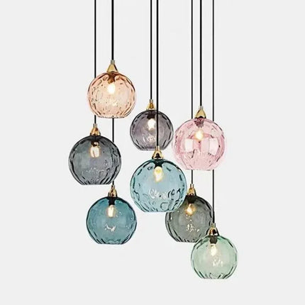 Suspension grappe de globes en verre soufflé bleu et vert avec embouts noirs sur fond blanc