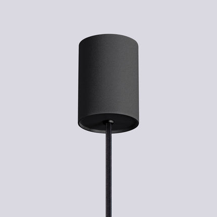 Suspension Halo 1 noire installée au-dessus d'une table à manger, ambiance chaleureuse