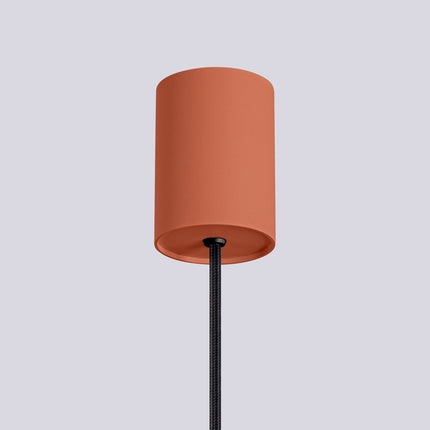 Suspension Halo 1 rouge ocre installée au-dessus d'une table à manger, ambiance chaleureuse