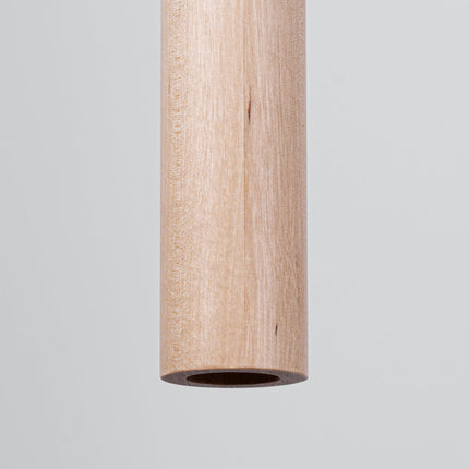 Gros plan sur l'embout d'un tube en bois naturel de la suspension Halo, grain et texture du bois visibles