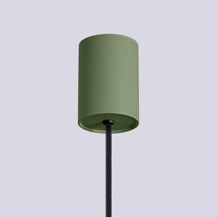 Suspension Halo 1 vert olive installée au-dessus d'une table à manger, ambiance chaleureuse