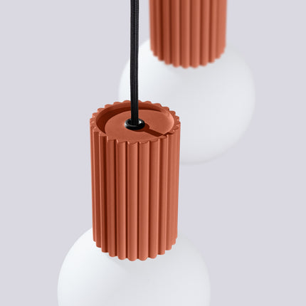 Suspension Halo 2 globes en grappe rouge ocre sur fond coloré, vue de trois quarts