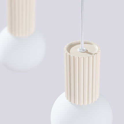 Suspension Halo 2 globes sur barre beige sur fond coloré, vue de trois quarts