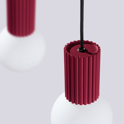 Suspension Halo 2 globes sur barre bordeaux sur fond coloré, vue de trois quarts