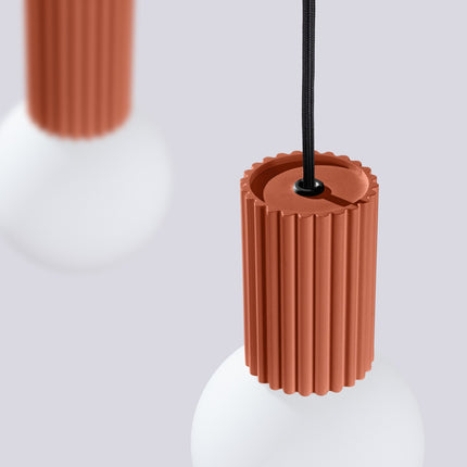 Suspension Halo 2 globes sur barre rouge ocre sur fond coloré, vue de trois quarts