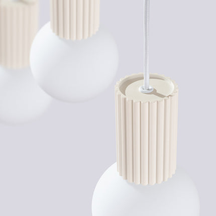 Suspension Halo 3 globes sur barre beige sur fond coloré, vue de trois quarts