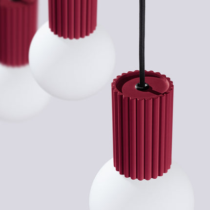 Suspension Halo 3 globes sur barre bordeaux sur fond coloré, vue de trois quarts