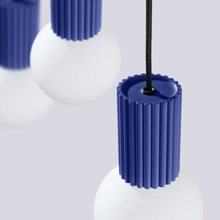 Suspension Halo 3 globes sur barre outremer sur fond coloré, vue de trois quarts