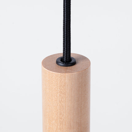 Gros plan sur l'embout d'un tube en bois naturel de la suspension Halo, grain et texture du bois visibles