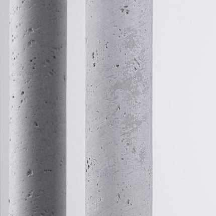 Gros plan sur la texture brute et minérale du béton des tubes de la suspension Halo