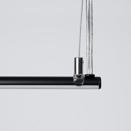 Suspension Ligne Minimaliste noire allumée vue en angle, fine barre linéaire suspendue
