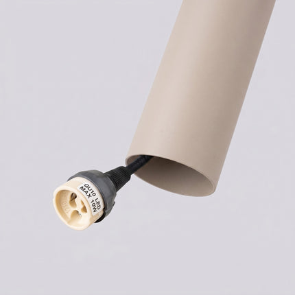 Suspension Long Cylindre taupe sur fond coloré, vue de trois quarts