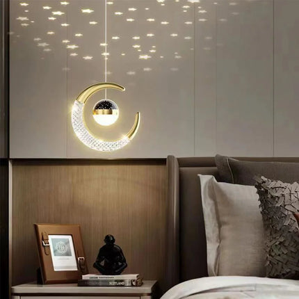 Suspension lune et étoile LED dorée éclairant un chevet en bois dans une chambre chaleureuse