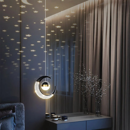 Suspension lune LED noire projetant un ciel d'étoiles sur un mur de chambre le soir