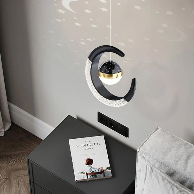 Suspension lune et étoile LED noire projetant des étoiles au-dessus d'une table de chevet