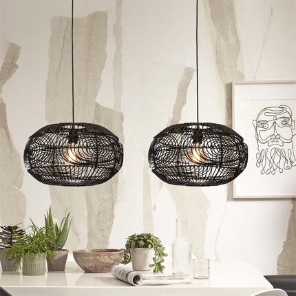 Two black woven rattan Madeira pendant lights installed as a duo above a table, minimalist interior