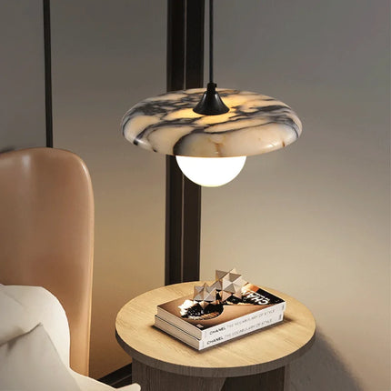 Suspension en marbre veiné dans une ambiance tamisée près d'une table basse en bois