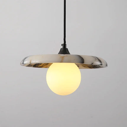 Suspension en marbre blanc veiné avec globe en verre opalin allumé, monture noire, sur fond clair