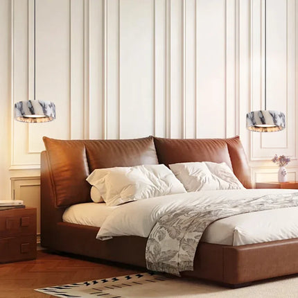 Deux suspensions en marbre naturel de part et d'autre d'une tête de lit en cuir cognac