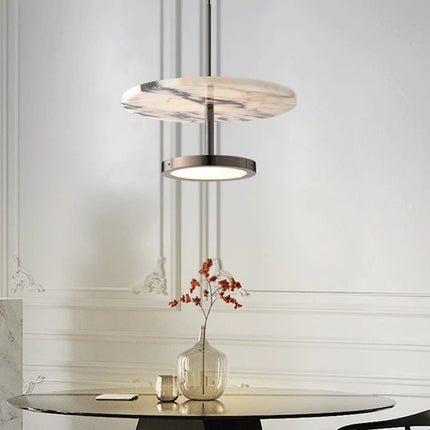 Suspension disque en marbre au-dessus d'une table ronde décorée, style japandi épuré