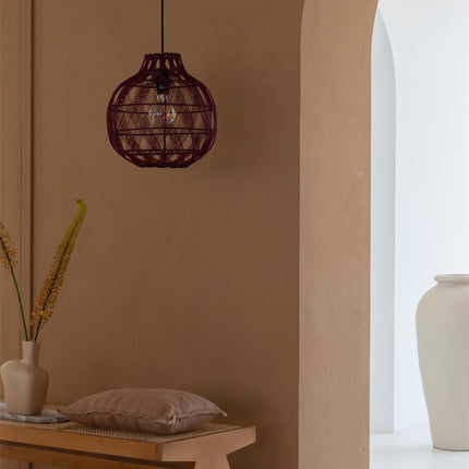 Suspension Mendoza bambou tressé bordeaux allumée devant un mur terracotta, ambiance chaleureuse