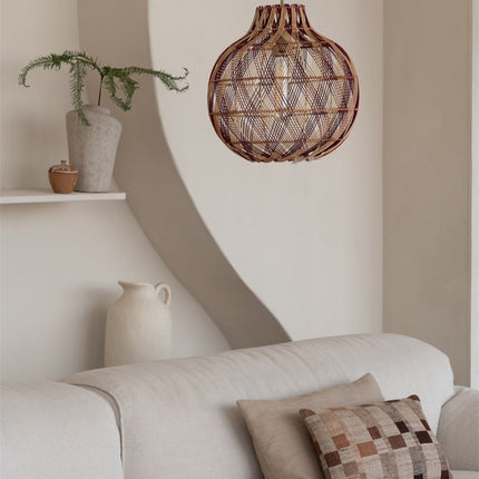 Suspension globe en bambou tressé au-dessus d'un canapé dans un salon aux tons naturels