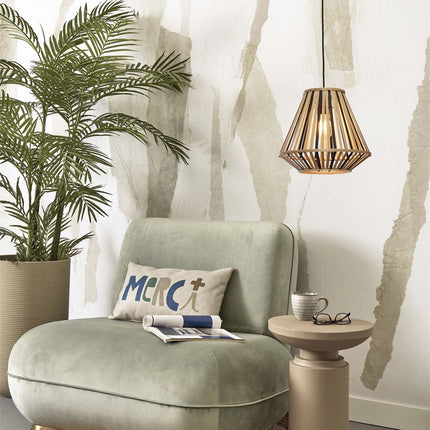 Suspension Merapi bambou noir et naturel au-dessus d'un fauteuil vert, ambiance salon chaleureuse et cosy.