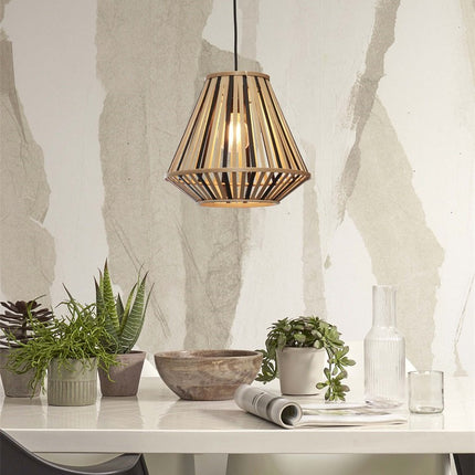 Suspension Merapi en bambou éclairée au-dessus d'une table blanche, entourée de plantes vertes et d'un bol en bois.