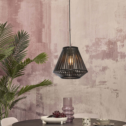 Suspension Merapi bambou noir au-dessus d'une table ronde, mur rosé texturé, ambiance chaleureuse