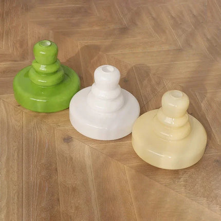 Trois abat-jours en verre soufflé vert, blanc et crème posés au sol, détail de la forme étagée
